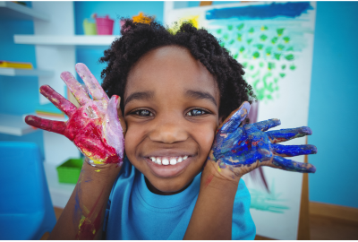 happy boy with red paint on his right hand and blue paint on his left hand
